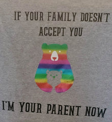 A grey shirt with text that reads "IF YOUR FAMILY DOESN'T ACCEPT YOU, I'M YOUR PARENT NOW" In between the lines of text is an image of a rainbow bear hugging the outline of a grey cub.