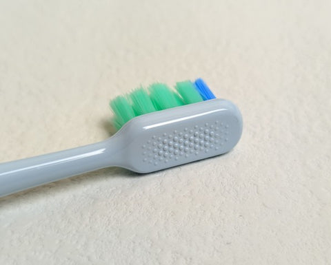牙刷的背面設有凹凸顆粒，可以用來輕輕刮擦舌頭