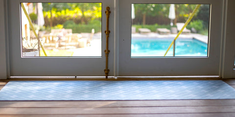 Machine washable Un-Rug is a low-profile and rubber backed doormat placed at double doors that leads to a swimming pool.