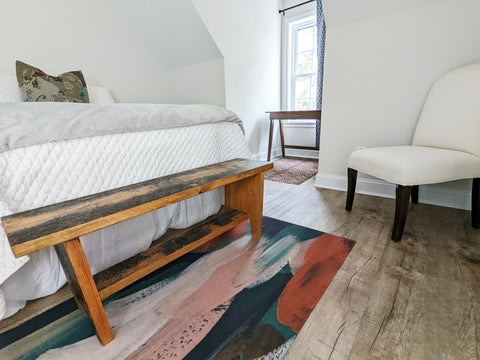 Low profile floor mat with abstract painting printed shown at the end of a bed.