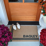 Personalized doormat in brown and black colorway placed in front of front door.