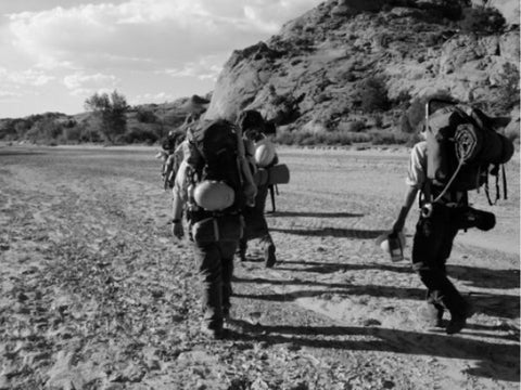 People with backpacks walking black and white