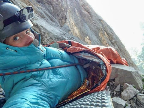 Woman camping in bivvy on cliff edge