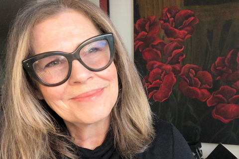 JoAnn Fowler, celebrity makeup artist and natural makeup brand founder, gazing while in front of red flower painting