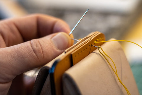 Hands of a leatherworker saddle stitching a small wallet