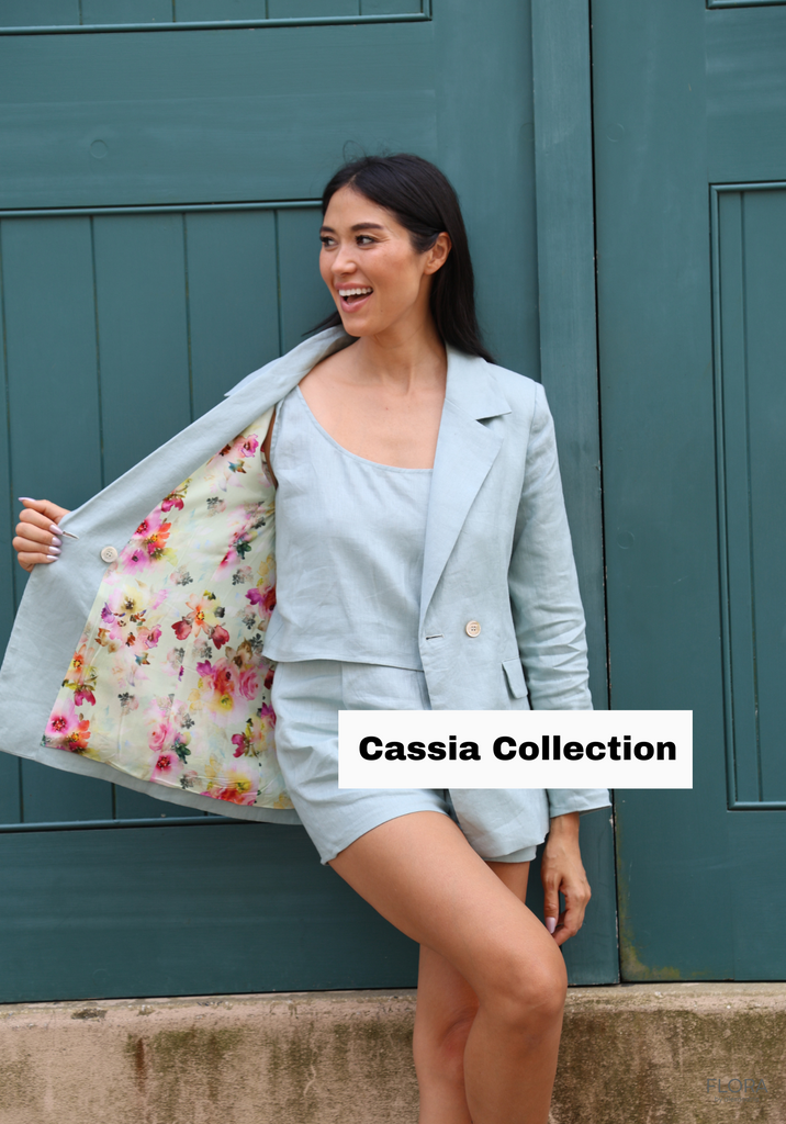 Asian looking girl modeling a blue linen blazer and short set. The linen blazer features a bright pink and green floral interior lining.