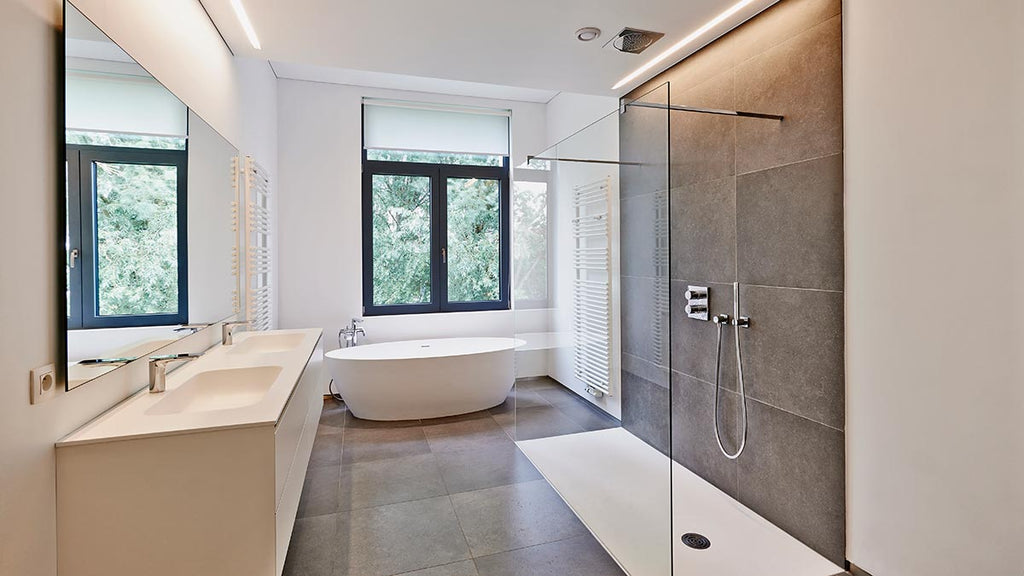 Modern bathroom with glass shower and tub, two sinks, mirror, window with trees, tiled floor, white radiator, and white bathtub.