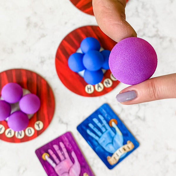 Woman playing Handy, the team-building balancing game. If you like Twister, you'll love this variation where players draw cards to see which balls to balance with other players using hands.