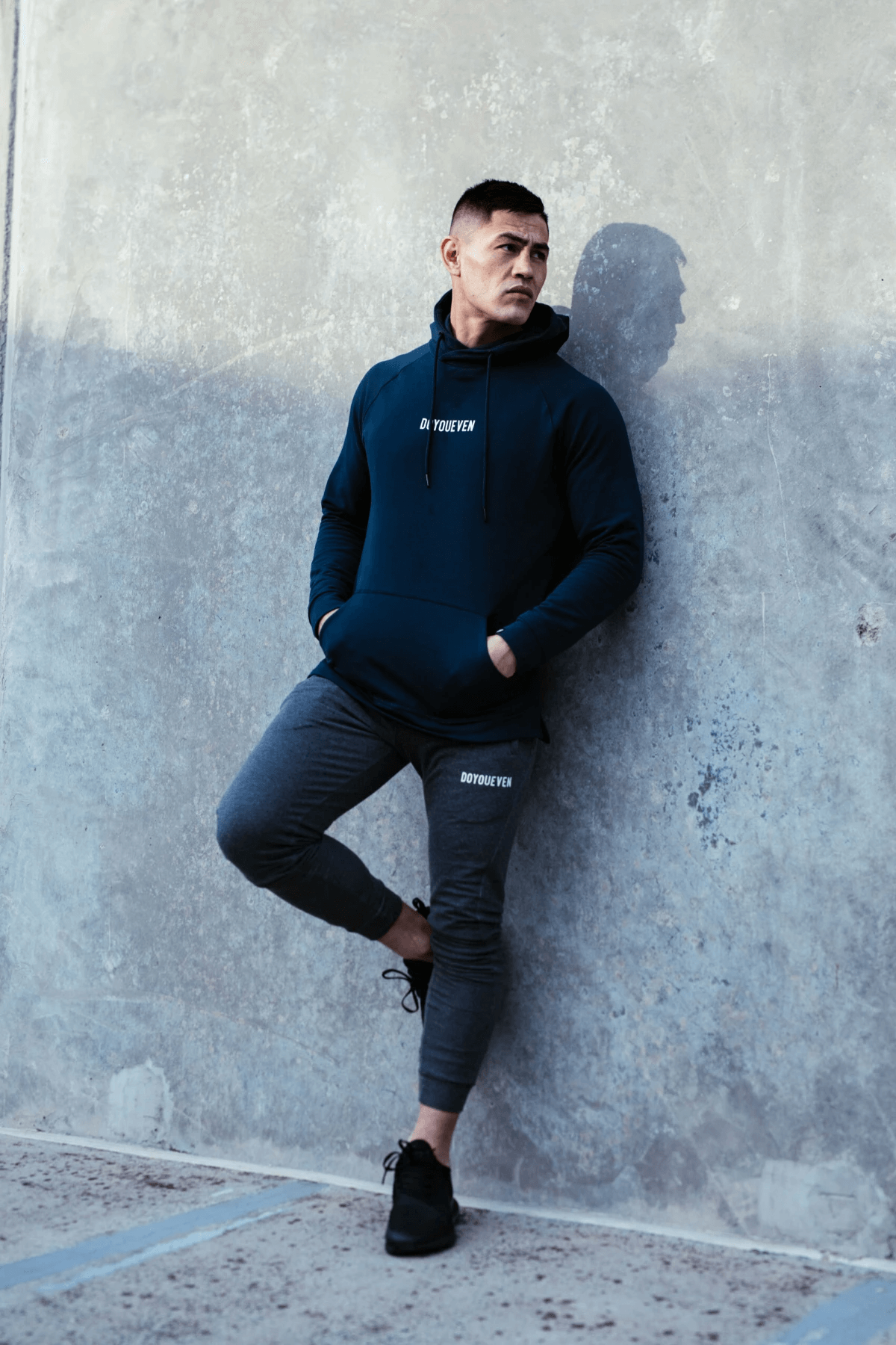 Male Fitness Model poses against a concrete wall wearing Doyoueven Activewear