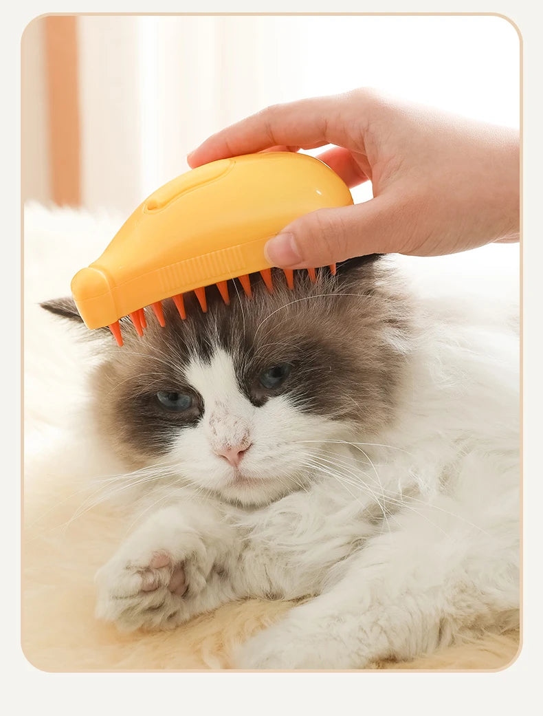 A fluffy cat is being groomed with the 3-in-1 Electric Pet Grooming Brush - Cat Steam Brush for Massage, Hair Removal, and More! from The Stuff Box. A hand is holding the brush, gently combing through the cat's fur.