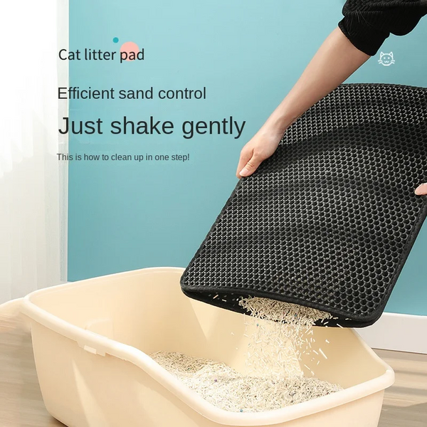 A person is shaking a black Waterproof Cat Litter Mat by The Stuff Box with a Double Layer Design over a beige litter box. The mat, made from Cat Friendly Material, is designed for efficient sand control, with instructions to "just shake gently" displayed on the image.