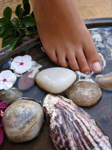 bare toes are dipping into water surrounded by rocks and flowers