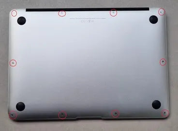 una MacBook Pro boca abajo en un laboratorio de Prime Tech Support con varias<!--nl--> áreas con círculos rojos que indican tornillos. en miami florida
