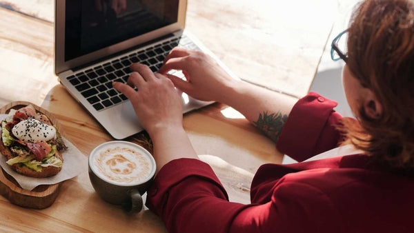 MacBook Pro user with a coffee next to it. Coffee Liquid Damage risk for a MacBook Pro