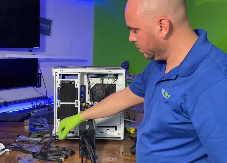 Técnico de Prime Tech Support Miami, Florida, instalando de manera experta una <!--nl--> unidad de fuente de alimentación (PSU) en una computadora para juegos.