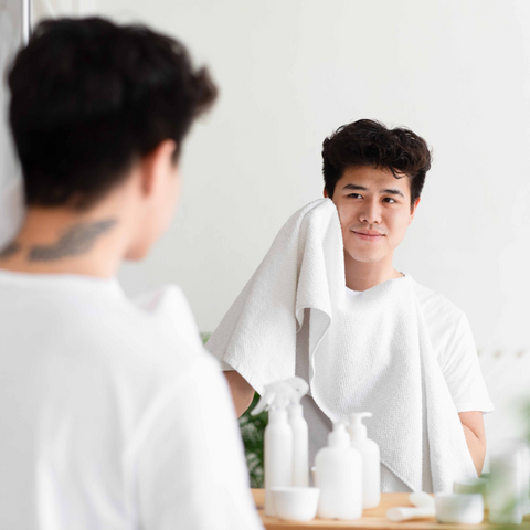 man patting face dry with towel