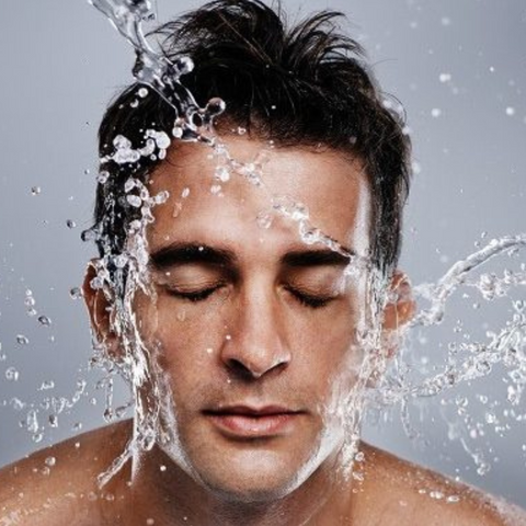 man with water splashing his face