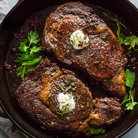 cooked ribeye steak with butter in pan