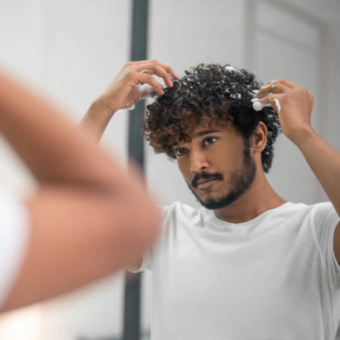 man styling hair with product