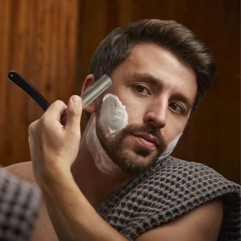man shaving using straight razor
