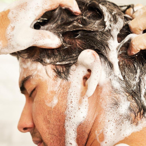 man shampooing hair in shower