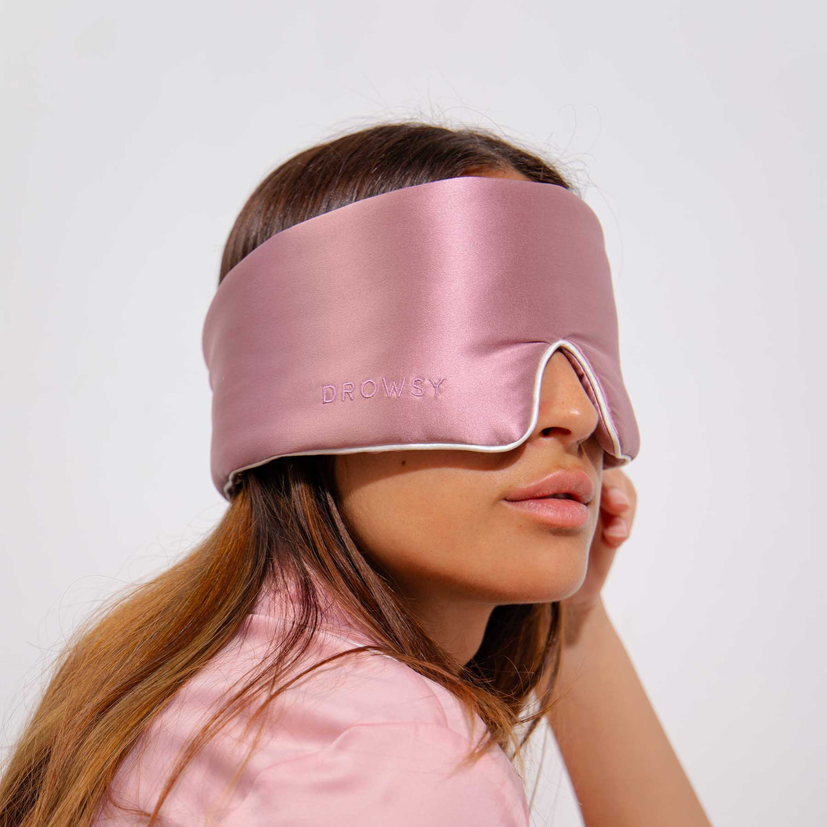 Model with pink Drowsy sleep mask covering eyes 