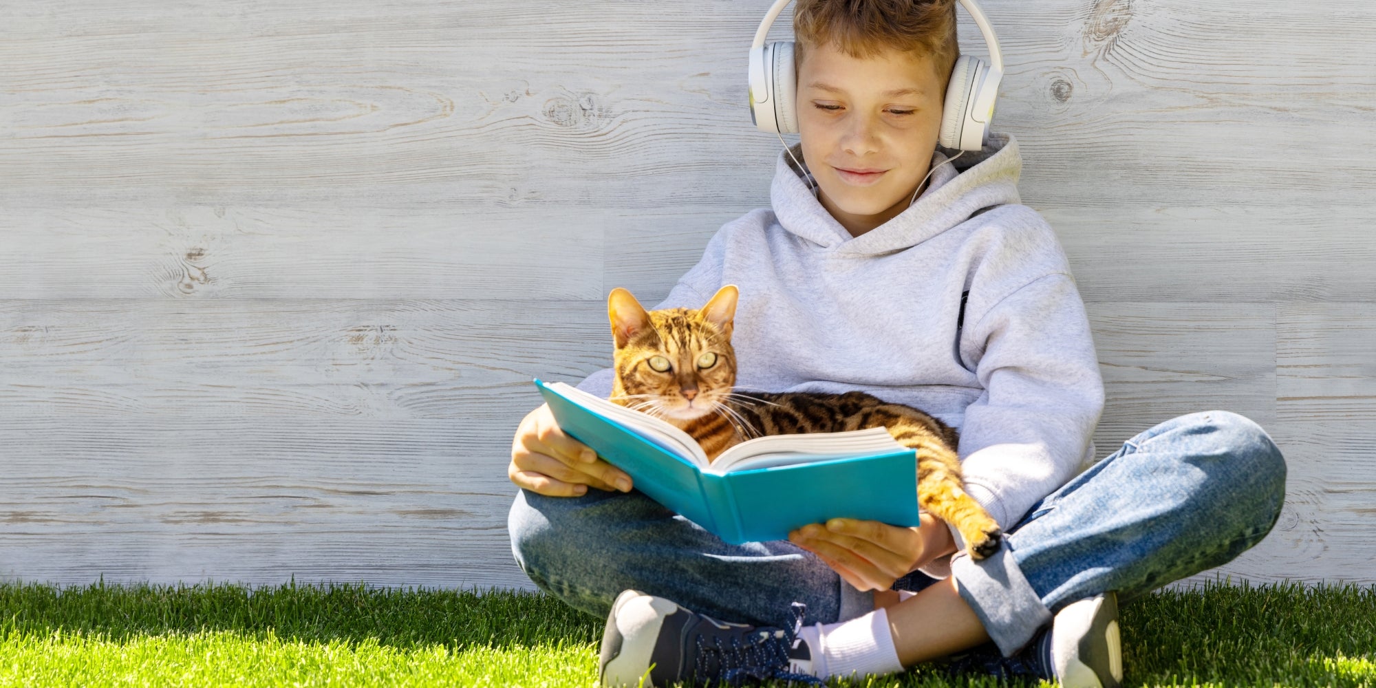 Un niño y un gato leyendo un libro sobre la hierba