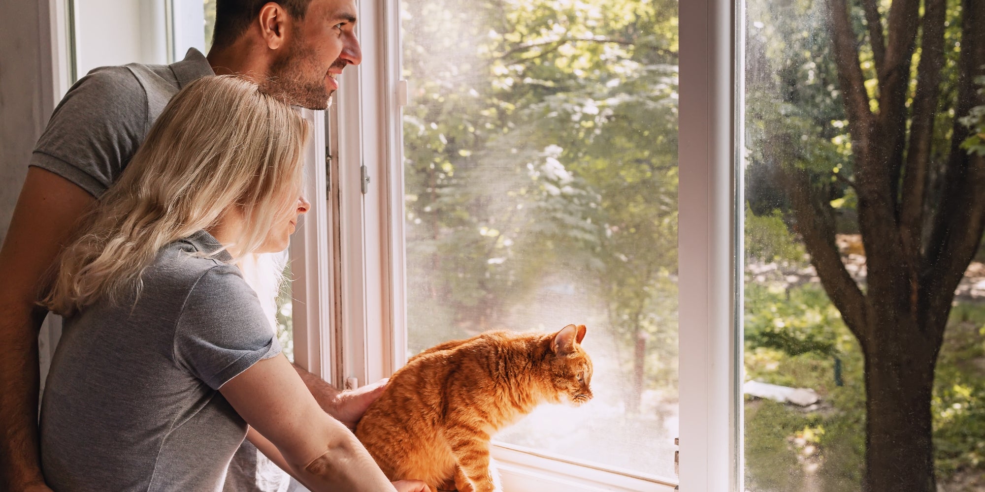 Pareja joven junto a la ventana con su gato