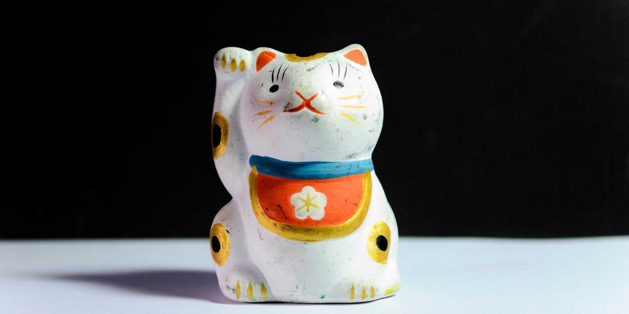 Figurita Maneki-Neko sobre superficie blanca