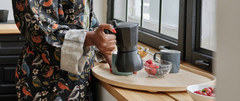 woman making espresso-style coffee at home with moka pot