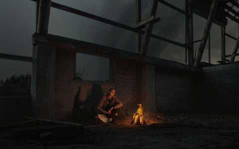 Woman sitting by fire in run down building