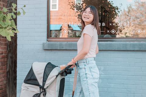 Woman walking pet stroller outside.