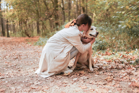 Woman hugging dog on a trail during fall with leaves everywhere.