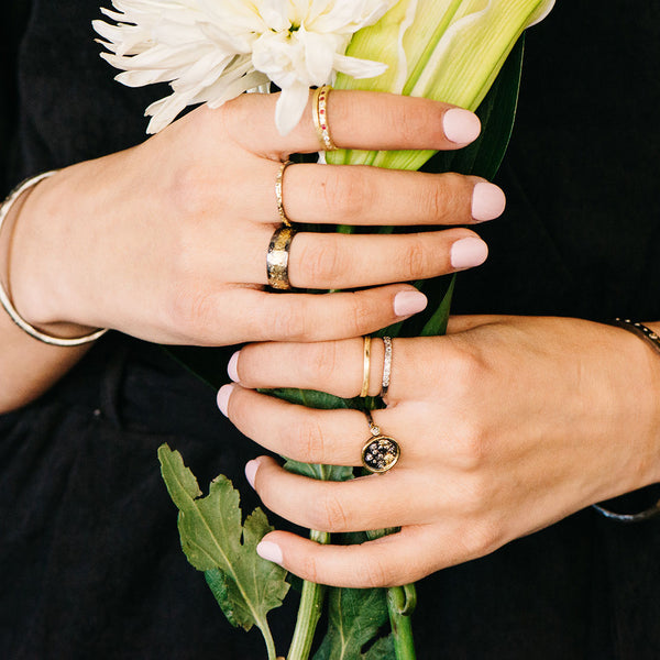 hands holding flowers with silver and gold rings