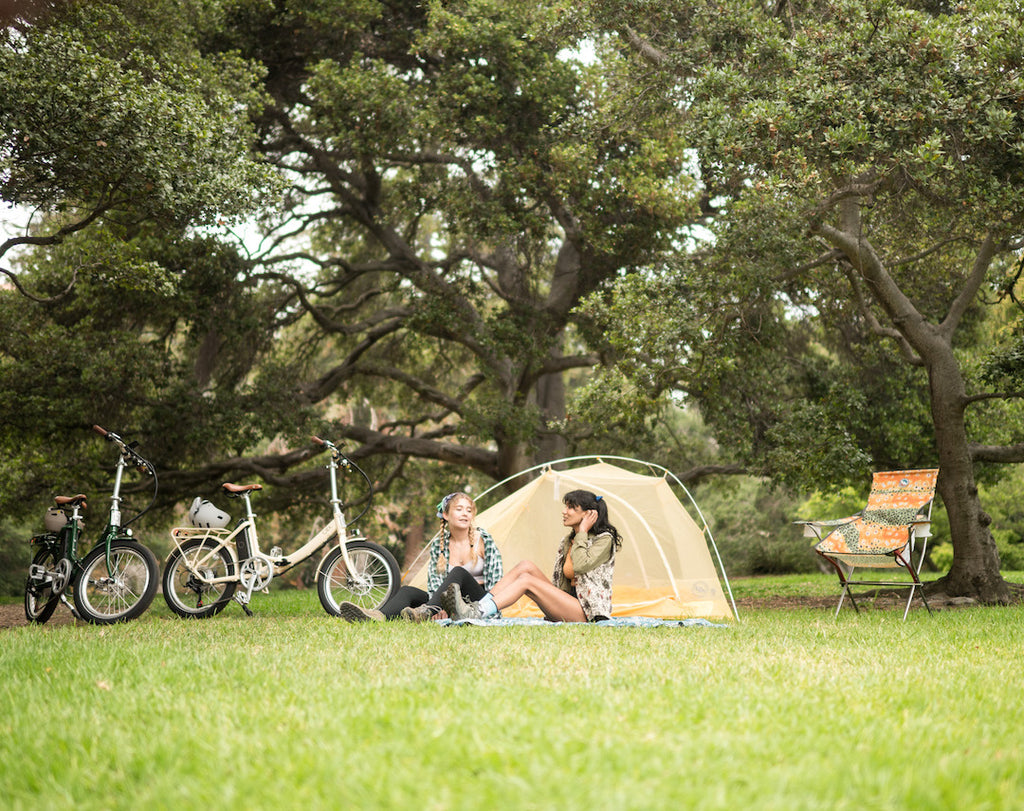 women sitting outside tent with bikes