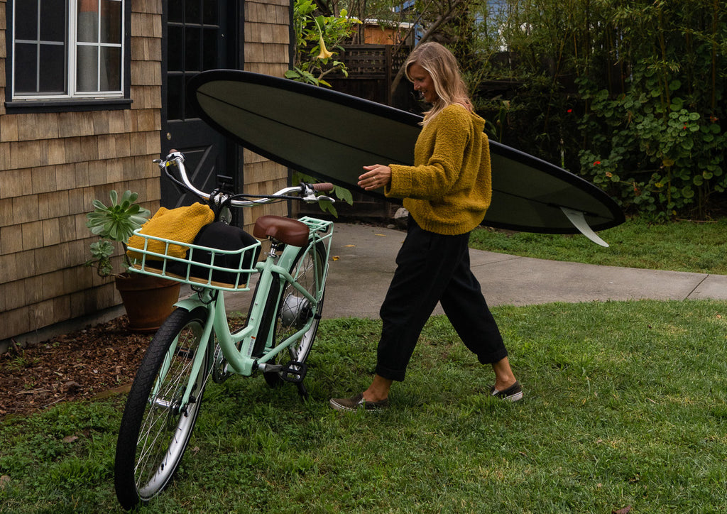 woman with surf board and bike