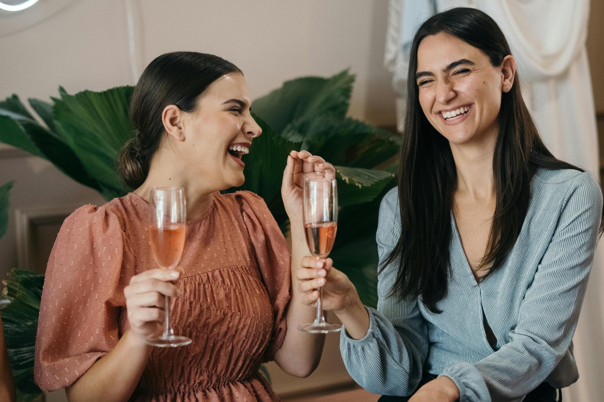 Deux invitées du mariage qui rient ensemble autour d'un verre