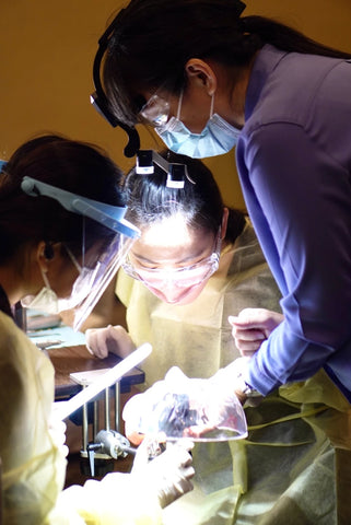 Two femal dental students are watching a dental lecturer and learning how to use mr Bur dental burs during a dental workshop