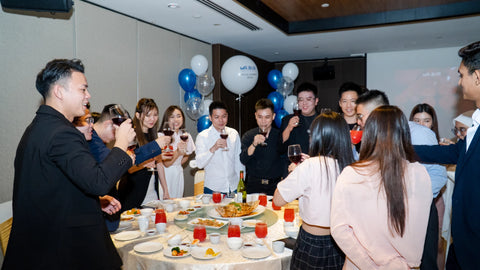 The employees of mr bur celebrating Chinese new year while holding up glasses of red wine they are happy and smiling hoping for a good new year where they provide dentists around the world with the best dental burs at great prices