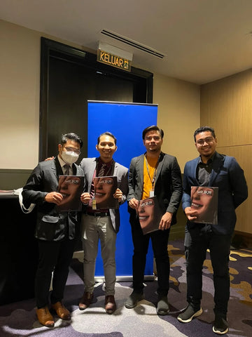 four men who are dentists are standing in front of a roll up stand and taking a picture while holding dental burs product catalog that is provided by mr bur the best international dental bur supplier in the world