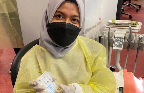 Dental student female wearing a hijab and a face mask and she is holding the dental burs sold by mr bur the best international dental bur supplier