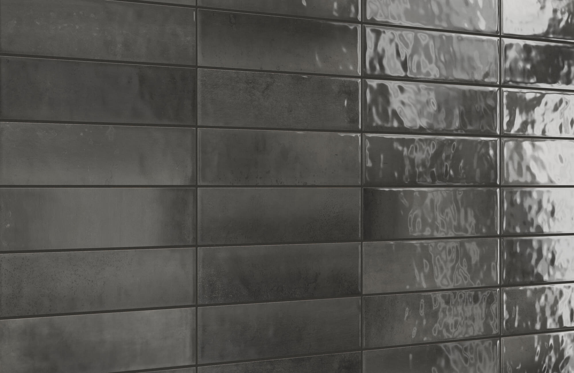 Close-up of black ceramic subway tiles featuring a mix of matte and glossy finishes that create texture, depth, and a moody modern vibe