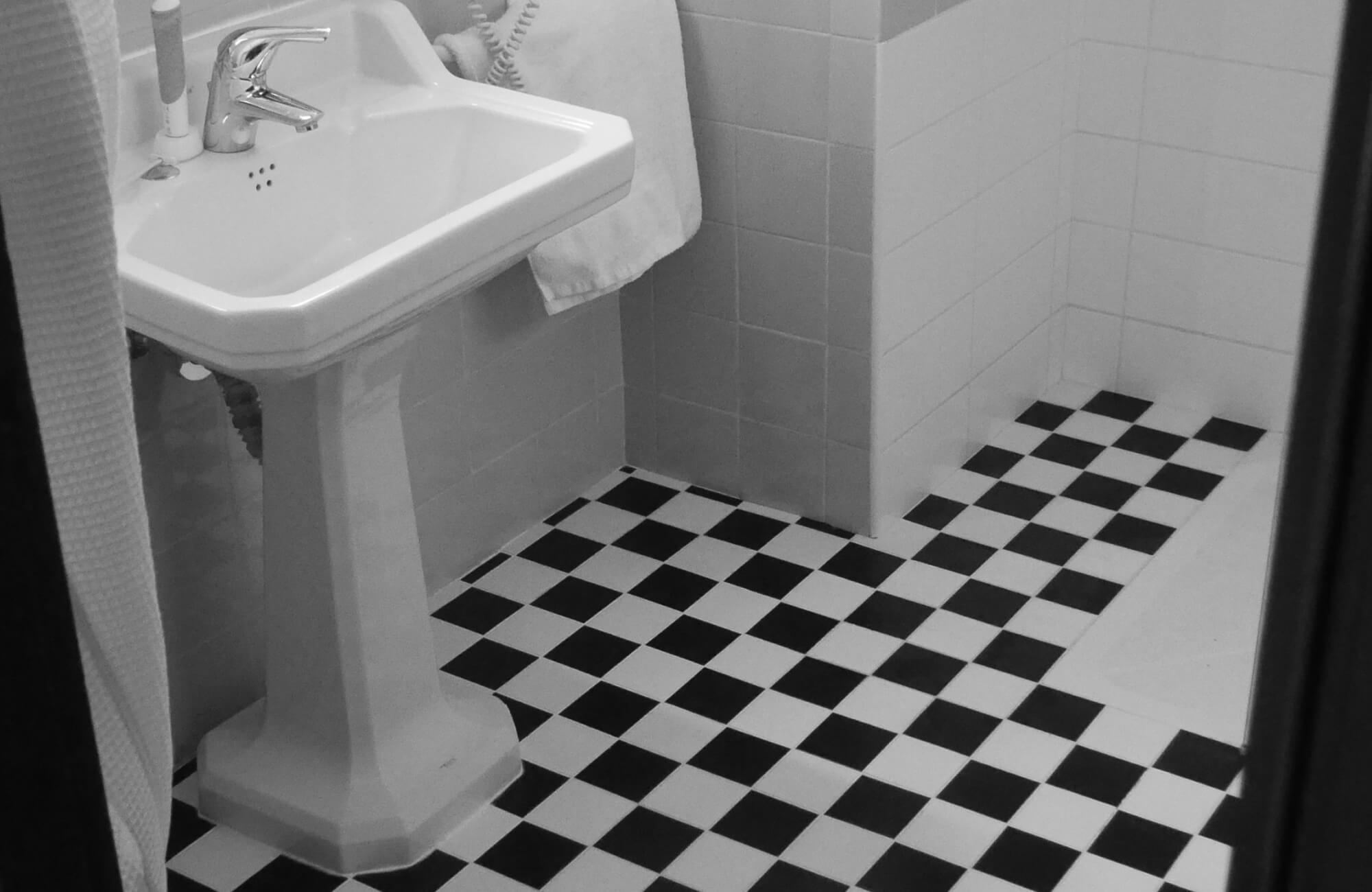 Small bathroom featuring a pedestal sink and black and white checkered tile flooring, offering a retro and classic vibe.