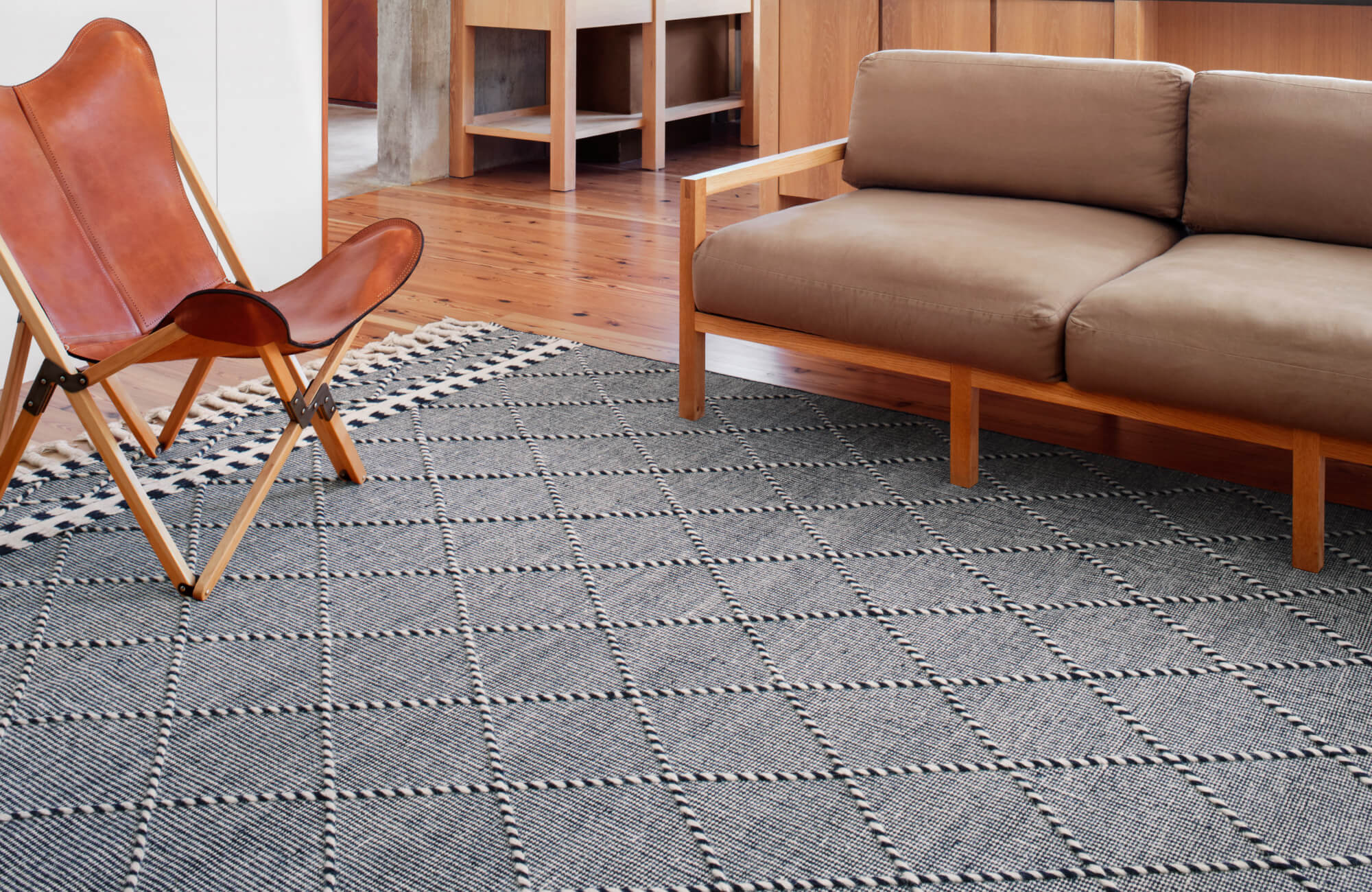 Textured high-quality cream area rug with raised diamond pattern in a cozy, modern living room with neutral décor.