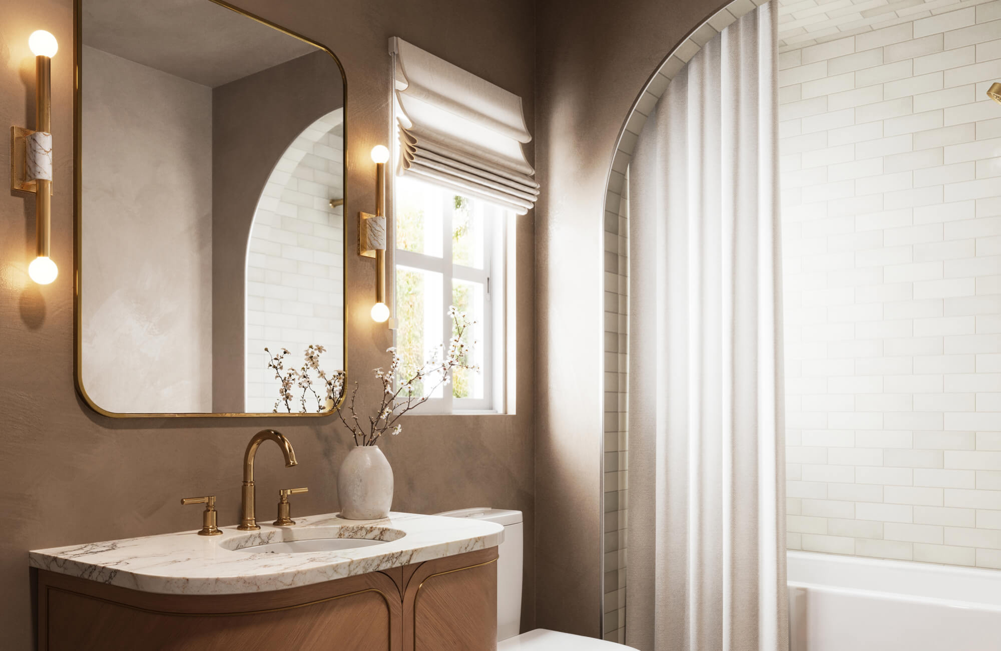 Softly lit bathroom with a gold-framed mirror, marble vanity, and twin globe sconces in a warm taupe setting, featuring an arched shower with subway tile.