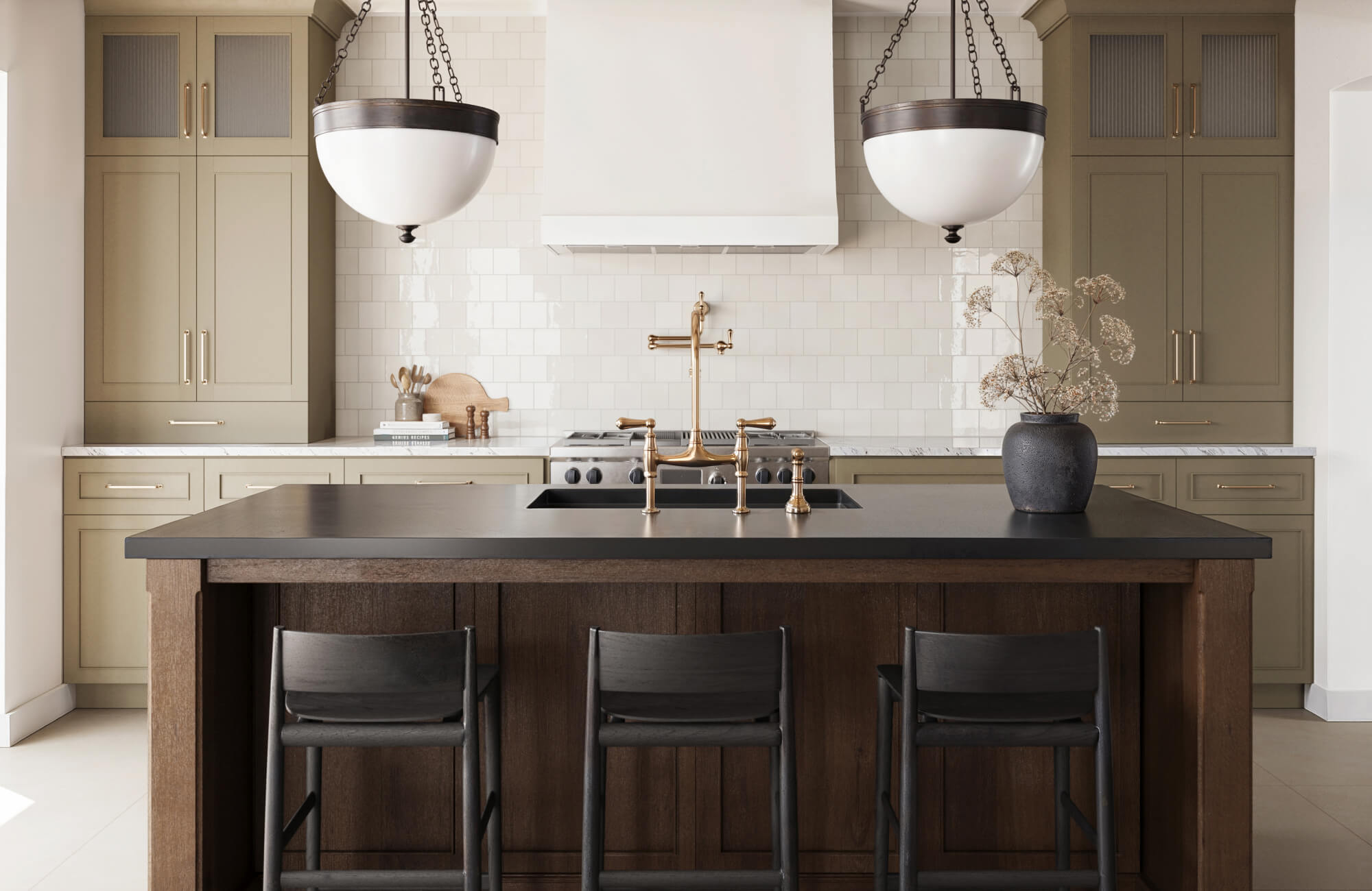 Pair of dome-shaped pendant lights with black trim and chain mounts illuminating a modern kitchen island.