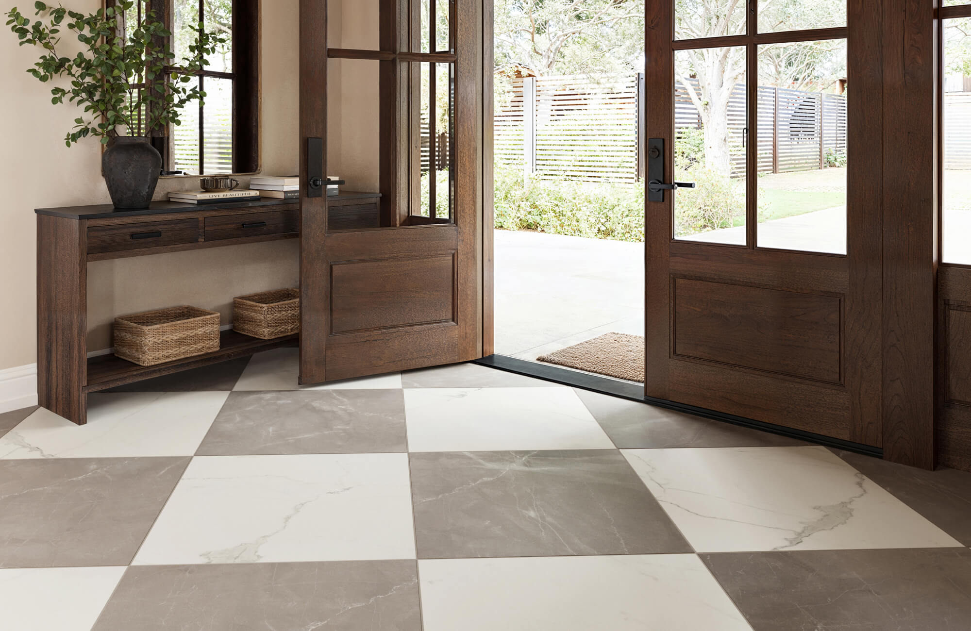 Spacious entryway with large brown and white checkered marble look tiles, complemented by a rustic wooden console table and open double doors