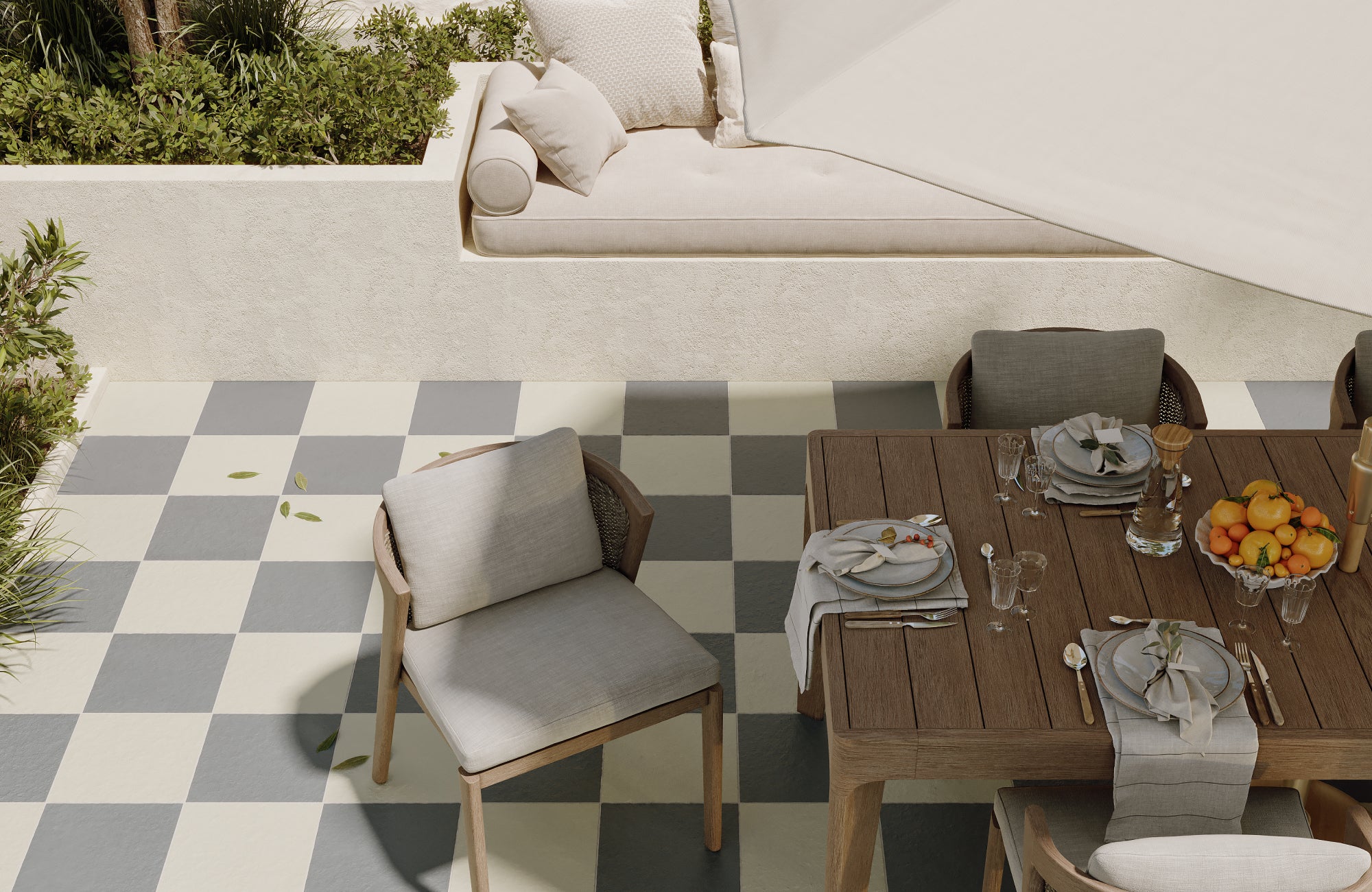 Outdoor dining patio with soft grey and white checkerboard tile and light wood furniture under a canopy.