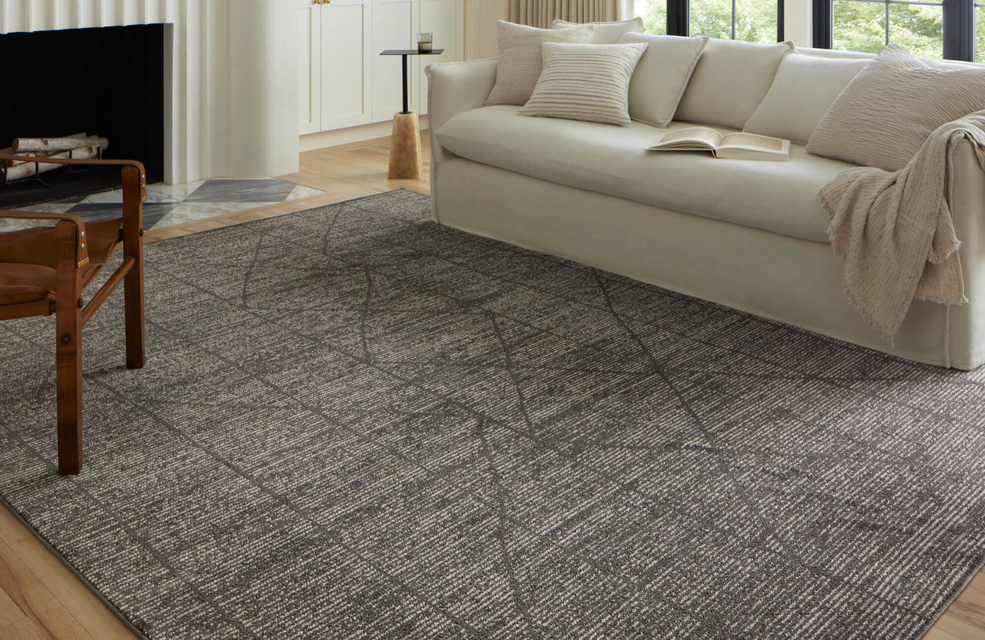 Modern living room with a dark textured rug, ivory sofa, and soft neutral accents for a warm, inviting ambiance.