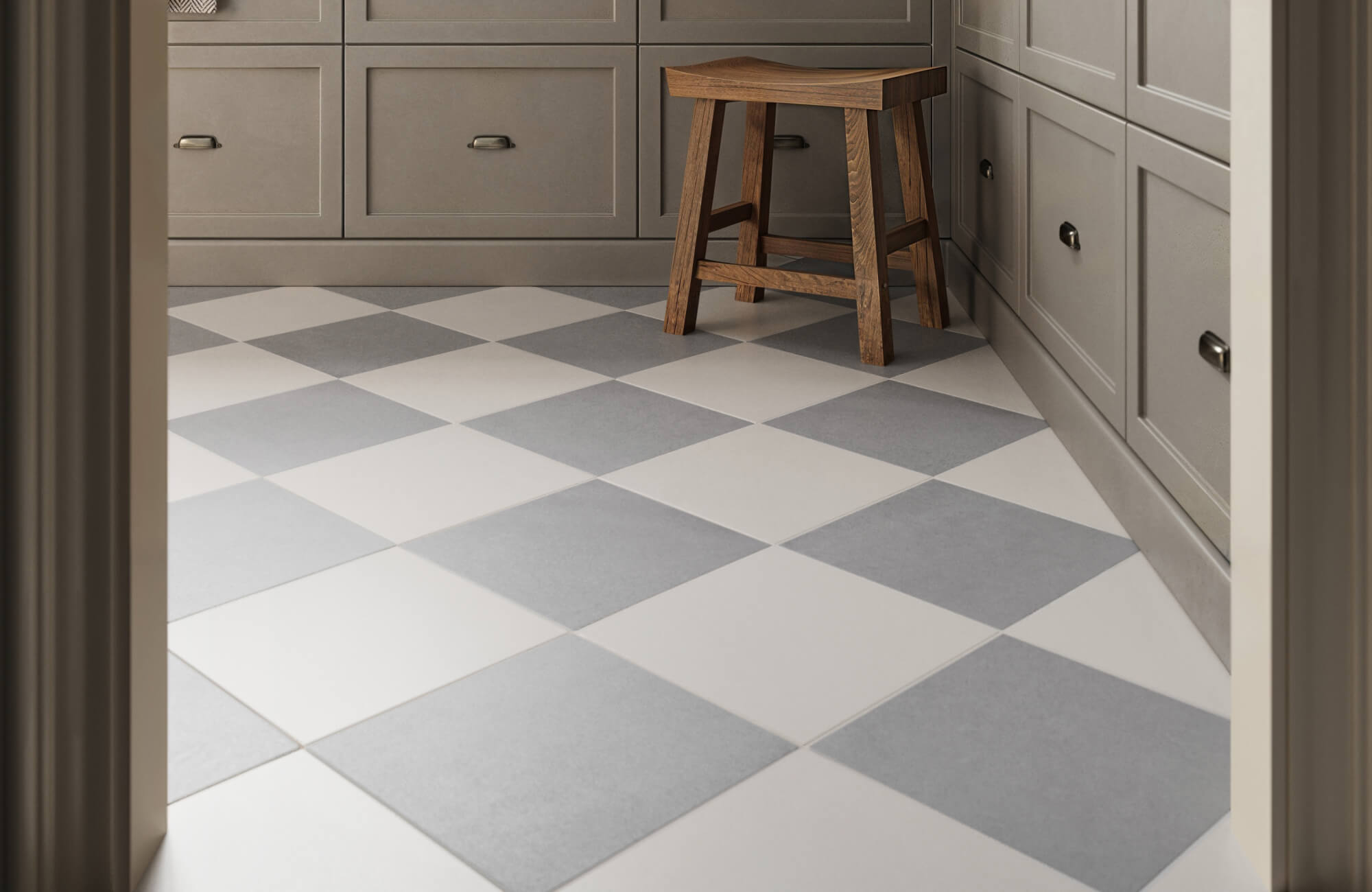 A cozy kitchen nook featuring light grey and white checkered floor tiles, complemented by neutral cabinetry and a rustic wooden stool